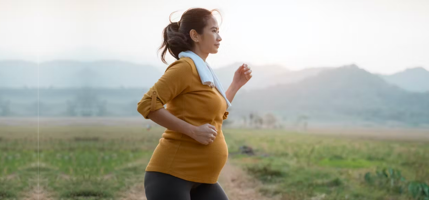 Pregnant East Asian woman running outdoors